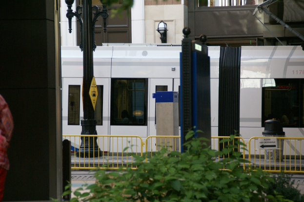 Frau auf der linken Seite einer Stadtstraße vor einem Zug umgeben von städtischen Elementen.