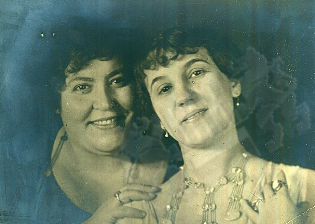 Zwei Frauen, die warm in die Kamera lächeln, auf einem alten Foto.