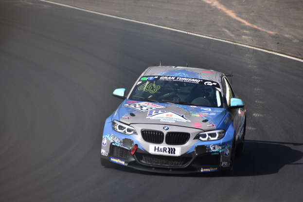 Ein BMW M2 GT3-Rennwagen auf einer Rennstrecke fahrend, mit Text und Zahlen auf seiner Karosserie.