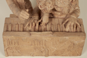 Eine steinerne Skulptur eines gekrönten Mannes in einem langen Gewand, der eine Piano spielt, mit detaillierten Händen und Gesichtsmerkmalen, geschlossenen Augen und leicht geöffnetem Mund, vor einem weißen Hintergrund.