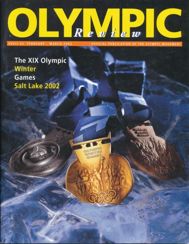 Buch mit dem Titel "Olympische Revue" und mehreren Medaillen in verschiedenen Größen und Farben auf dem Cover.
