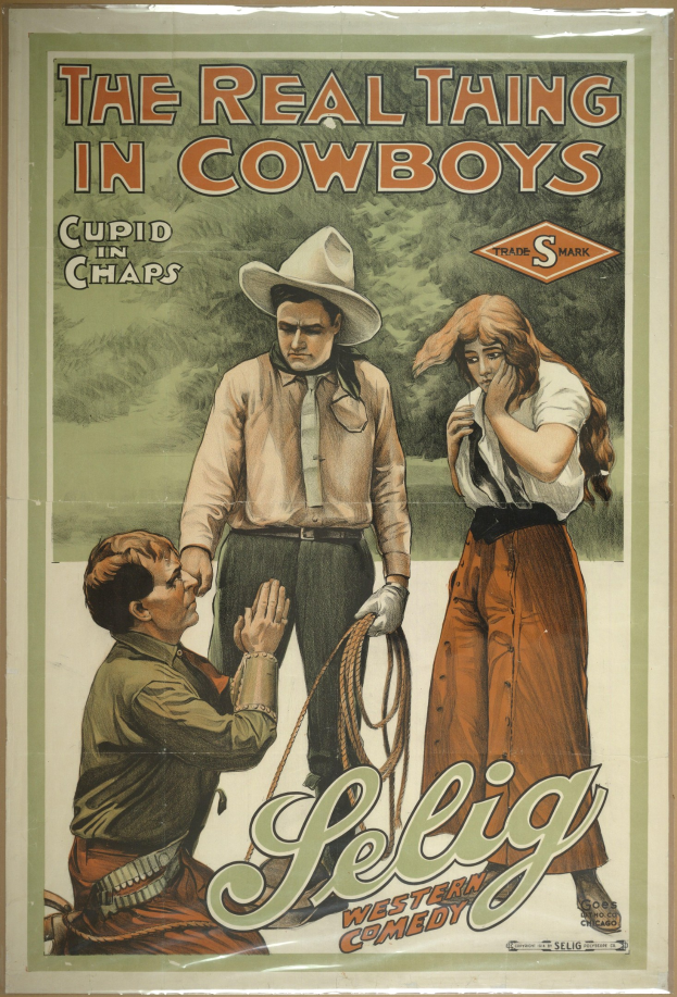 Plakat an einer Wand mit drei Personen - zwei Männer mit Cowboyhüten und eine Frau in einem langen Kleid - mit der schwarzen Schrift "Das echte Ding bei Cowboys" auf einem hellgelben Hintergrund.