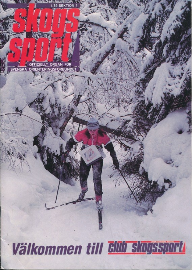 Eine Person in einer Mütze, die Ski-Stöcke hält und einen schneebedeckten Hügel hinabskiht, umgeben von schneebedeckten Bäumen, mit dem Text "Skogs Sport - Valkommen till Club Skogssport" unten.
