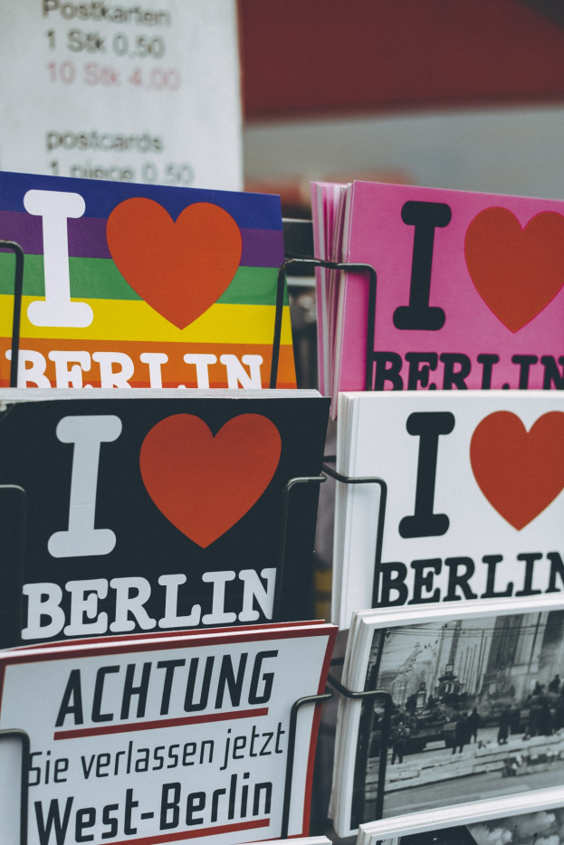 Ein Gestell mit Büchern und Postern, die den Text "Ich liebe Berlin" gegen einen leicht unscharfen, traumhaften Hintergrund zeigen.