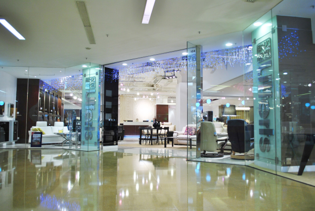 Innenansicht eines möblierten Ladens mit Stühlen, Sofas, Tischen und anderen Gegenständen, mit sichtbaren Boden- und Deckenlampen, identifiziert als Friseursalon durch ein Schild im Hintergrund.