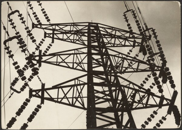 Schwarz-weiß-Foto eines Hochspannungsmasten mit Drähten vor einem Himmel, mit Text unten.