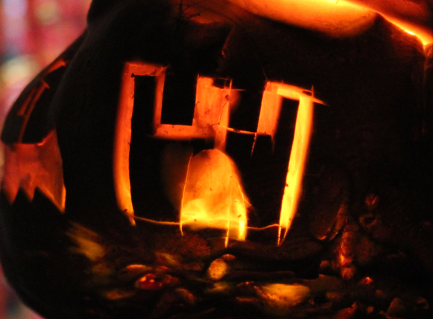 Ein Jack-o'-Lantern mit dem Wort "Halloween" darin, von innen beleuchtet, mit einem unscharfen Hintergrund.