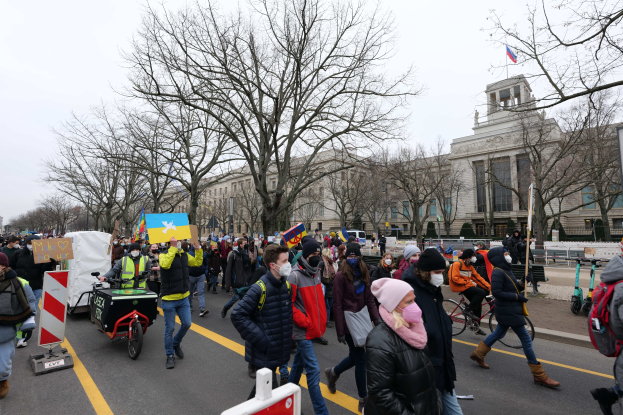 Eine große Gruppe von Menschen marschiert auf einer Straße in Washington, D.C. am 21. Januar 2020, hält Schilder und fährt Fahrräder, mit Bäumen und einem Gebäude im Hintergrund unter einem klaren blauen Himmel.