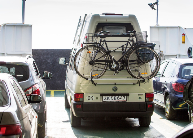Verschiedene Fahrzeuge, einschließlich Autos und Fahrräder in verschiedenen Farben, sind in der Mitte des Bildes positioniert.