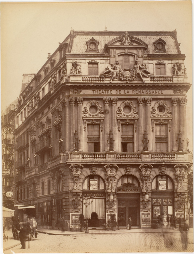 Schwarz-weiß-Foto des Théâtre de la Renaissance in Paris mit einer Fassade mit Fenstern, Säulen, Bögen und Skulpturen, mit ein paar Menschen und Fahrzeugen davor und dem Himmel im Hintergrund.
