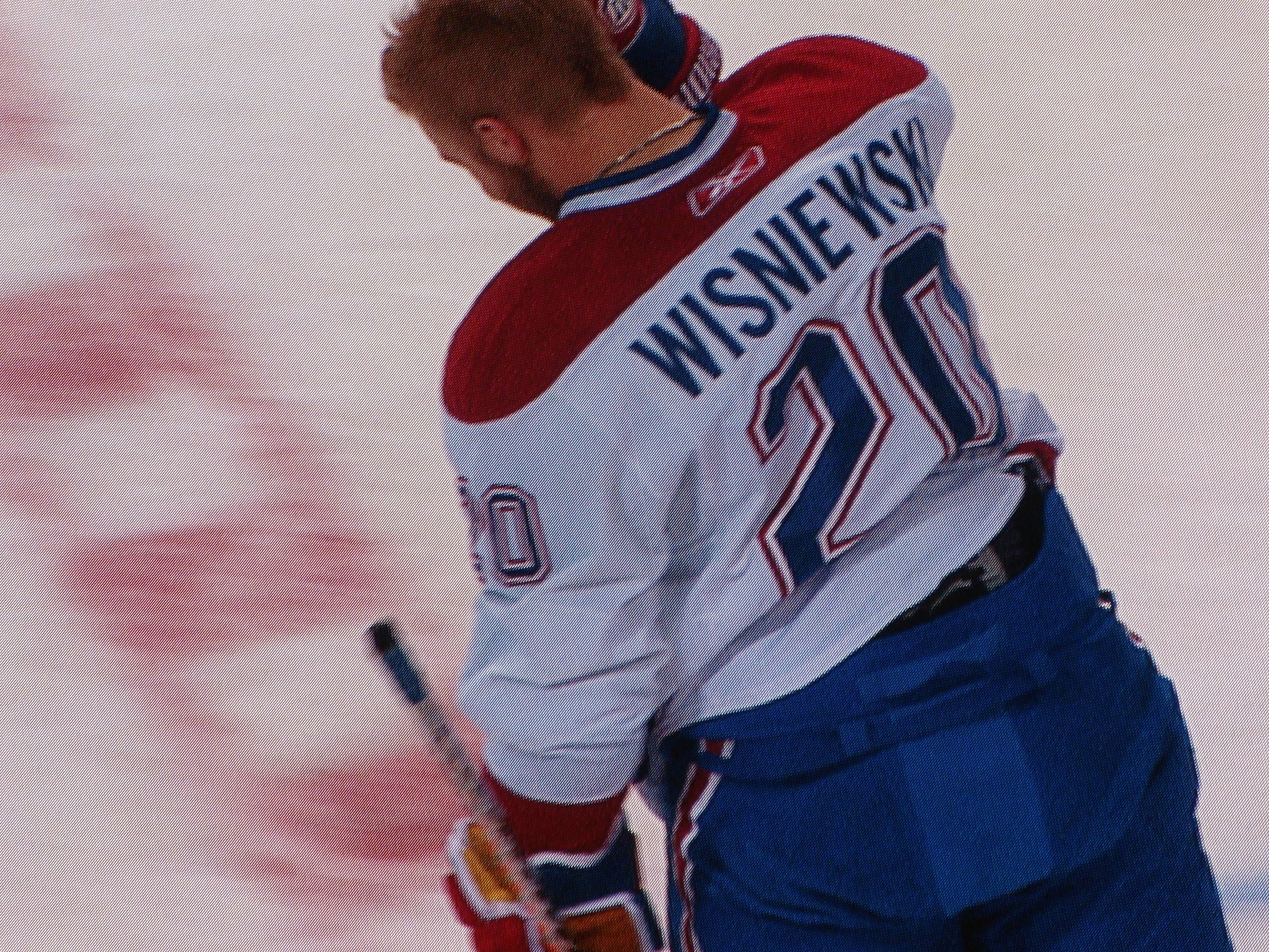 Professioneller Eishockeyspieler in einem "Wisniewski"-Trikot, der konzentriert auf dem Eis steht und einen Hockey-Schläger hält.