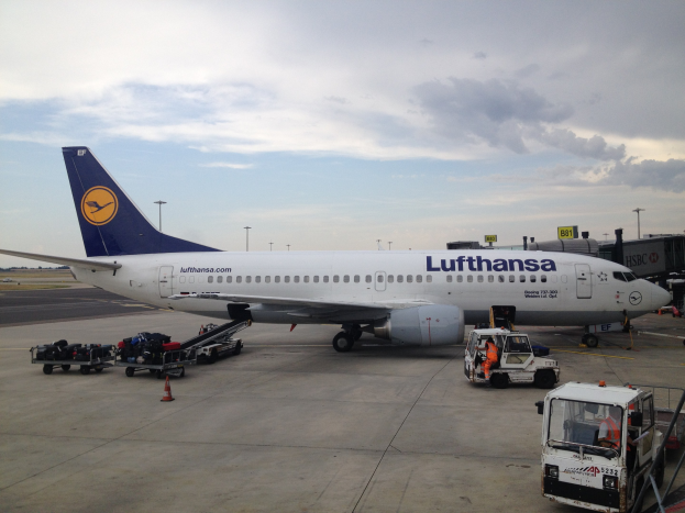 Lufthansa Airbus A320-200 am Frankfurter Airport mit Bodenfahrzeugen, Wagen, Verkehrskegeln, Beschilderung und einer bewölkten Himmel im Hintergrund.