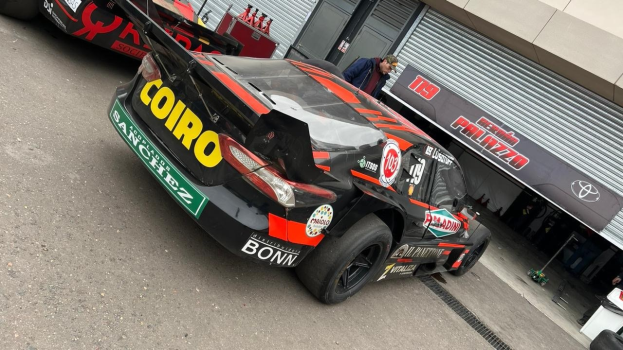 Gruppe von Autos vor einem Gebäude mit "Le Mans 2019"-Banner geparkt, Menschen drumherum bei Rennstart