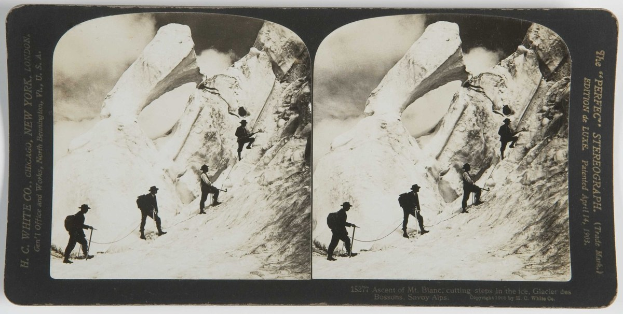 Schwarzes und weißes Foto einer Gruppe von Menschen, die eine schneebedeckte Bergwand mit sichtbaren Stufen im Eis im Hintergrund erklimmen.