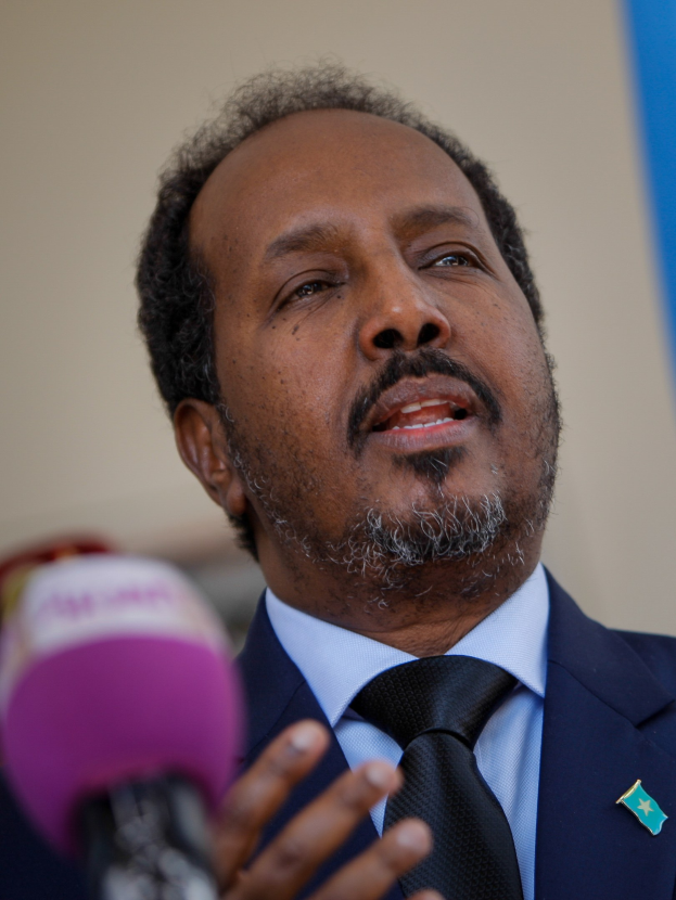 Ein Mann in Anzug und Krawatte, der in ein Mikrofon spricht und wahrscheinlich eine Zuschauermenge als Politologe anspricht.