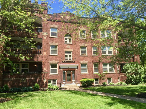 Großes Backsteingebäude mit grünem Rasen, Bäumen und einem klaren blauen Himmel in Chicago, Illinois, zur Miete verfügbar.