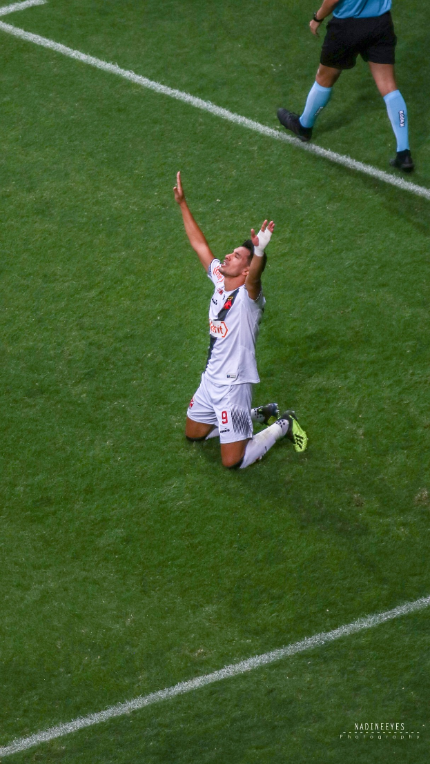 Ein Fußballspieler in Uniform kniet auf dem Boden und streckt die Arme aus, um zu feiern.