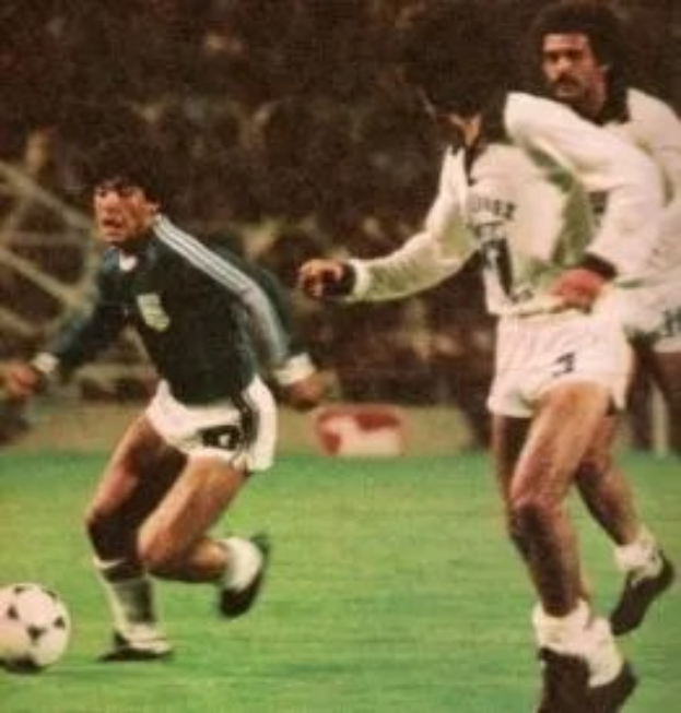 Eine Gruppe von Männern, die auf einem Feld Fußball spielen, mit einem Ball in der Mitte der Aktion.