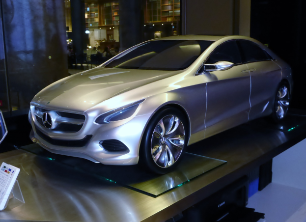 Ein schlankes, modernes Mercedes-Benz-Konzeptfahrzeug mit glänzender schwarzer Lackierung und Chromakzenten auf der Frankfurt Motor Show ausgestellt, umgeben von Menschen, Lichtern und anderen Gegenständen.