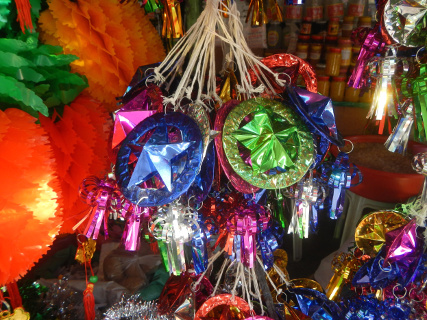Farbenfrohe Festschmuckdekorationen mit Papierlaternen und Bändern hängen von der Decke über Regalen mit Flaschen im Hintergrund.